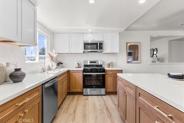 kitchen with white cabinetry, light countertops, a sink, appliances with stainless steel finishes, and brown cabinetry