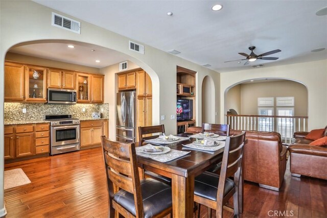 dining area featuring dark wood-style floors, visible vents, and arched walkways