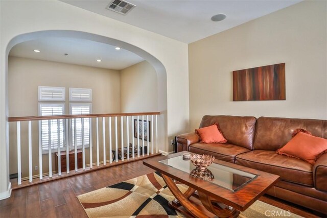 living room with wood finished floors, recessed lighting, arched walkways, and visible vents
