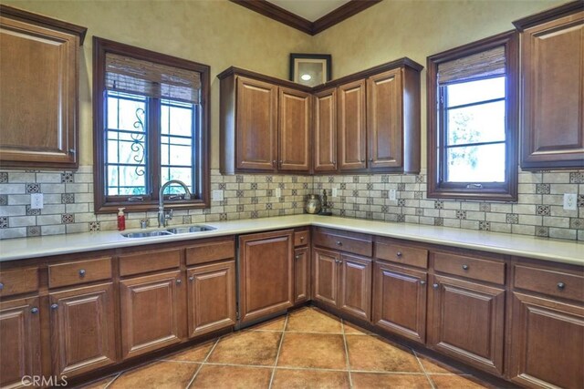 kitchen featuring ornamental molding, light countertops, tile patterned flooring, and a sink