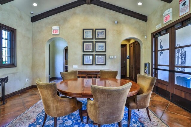 tiled dining area featuring baseboards, beamed ceiling, high vaulted ceiling, and arched walkways