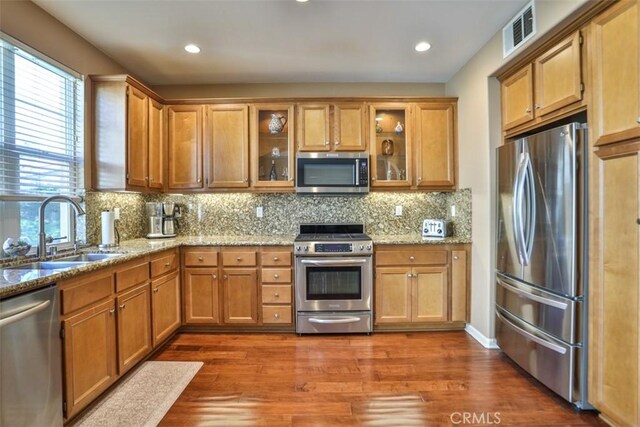 kitchen with stainless steel appliances, dark wood finished floors, backsplash, a sink, and visible vents