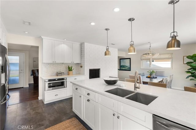 kitchen with a sink, hanging light fixtures, light countertops, and appliances with stainless steel finishes