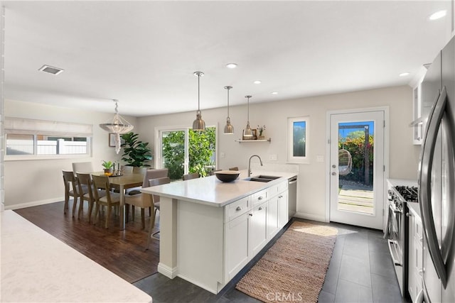 kitchen with a peninsula, visible vents, appliances with stainless steel finishes, light countertops, and a sink