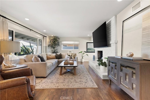 living room with visible vents, a brick fireplace, recessed lighting, and wood finished floors