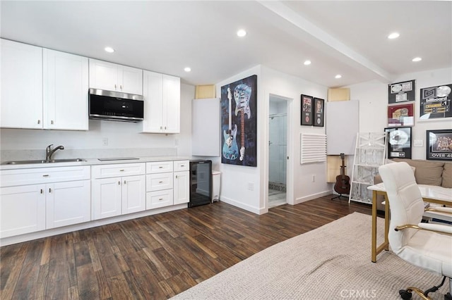 kitchen featuring a sink, white cabinets, beverage cooler, stainless steel microwave, and dark wood-type flooring