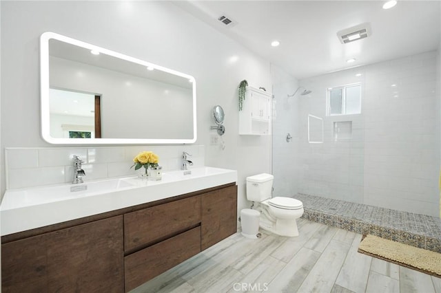 bathroom featuring walk in shower, visible vents, toilet, and a sink