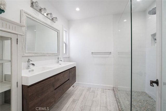 bathroom with walk in shower, wood finished floors, a sink, and double vanity