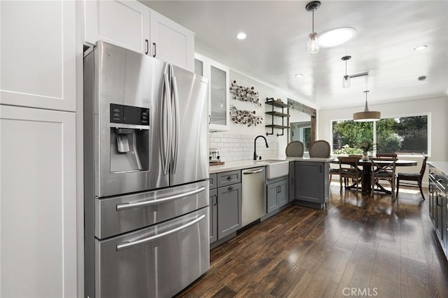 kitchen with dark wood-style floors, a sink, decorative backsplash, gray cabinets, and appliances with stainless steel finishes