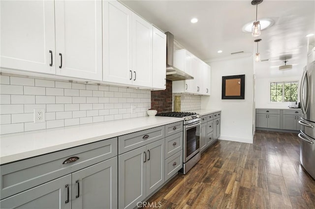 kitchen featuring wall chimney range hood, light countertops, appliances with stainless steel finishes, gray cabinetry, and dark wood-style floors