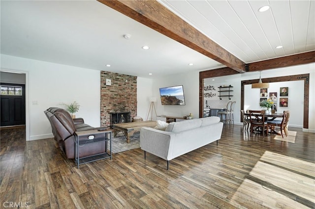 living area featuring wood finished floors, beamed ceiling, a fireplace, baseboards, and recessed lighting