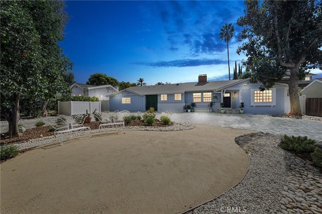 ranch-style home featuring a chimney, fence, a patio, and curved driveway