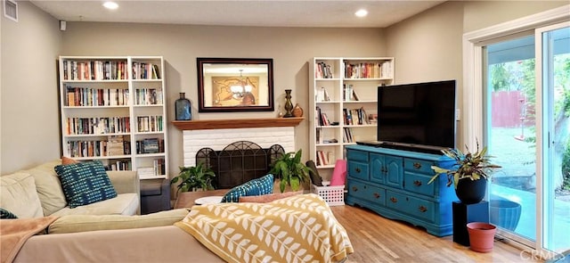 sitting room with wood finished floors, a brick fireplace, and recessed lighting