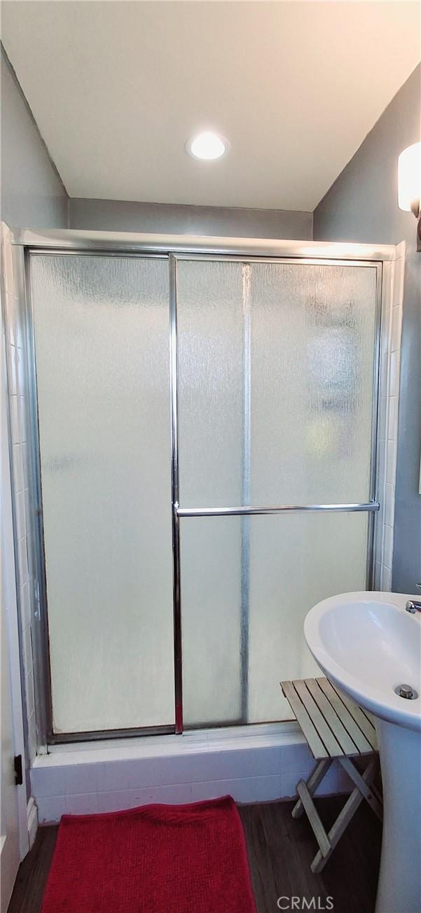 bathroom with wood finished floors and a stall shower