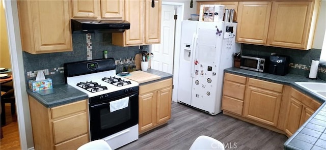 kitchen with extractor fan, range with gas cooktop, white refrigerator with ice dispenser, stainless steel microwave, and wood finished floors
