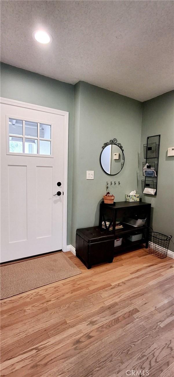 entrance foyer with baseboards, light wood-type flooring, a textured ceiling, and recessed lighting