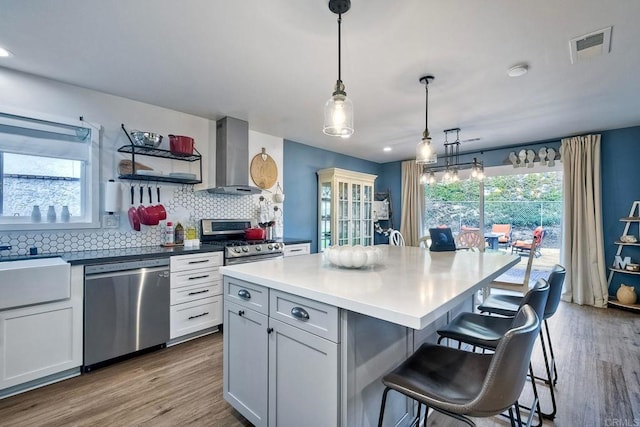 2760 Thunder Dr, Oceanside, CA 92056 - kitchen with appliances with stainless steel finishes, range hood, wood finished floors, a breakfast bar area, and backsplash