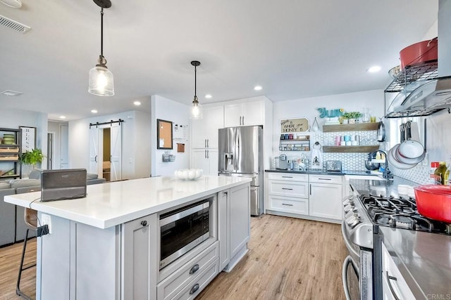 2760 Thunder Dr, Oceanside, CA 92056 - kitchen with stainless steel appliances, light wood finished floors, a barn door, white cabinetry, and recessed lighting