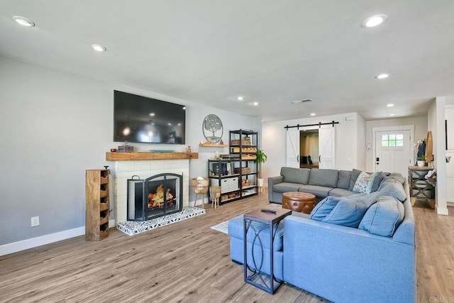 2760 Thunder Dr, Oceanside, CA 92056 - living area with a barn door, wood finished floors, a lit fireplace, and recessed lighting