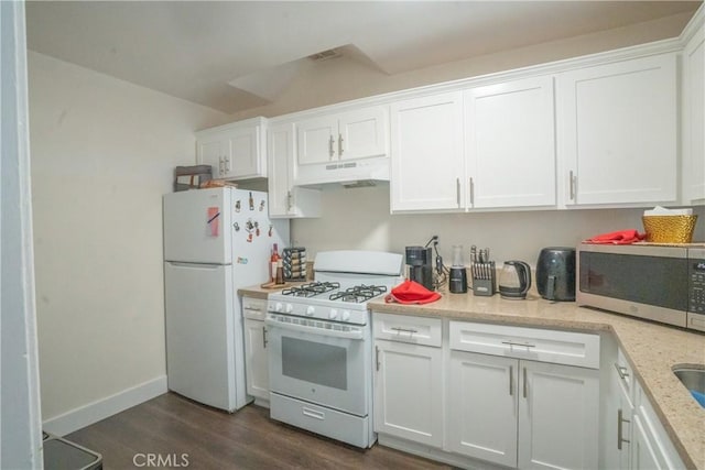 kitchen with light stone countertops, under cabinet range hood, white appliances, white cabinetry, and dark wood-type flooring
