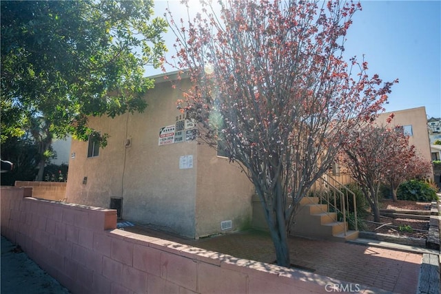 view of home's exterior featuring a patio, stucco siding, stairway, and fence
