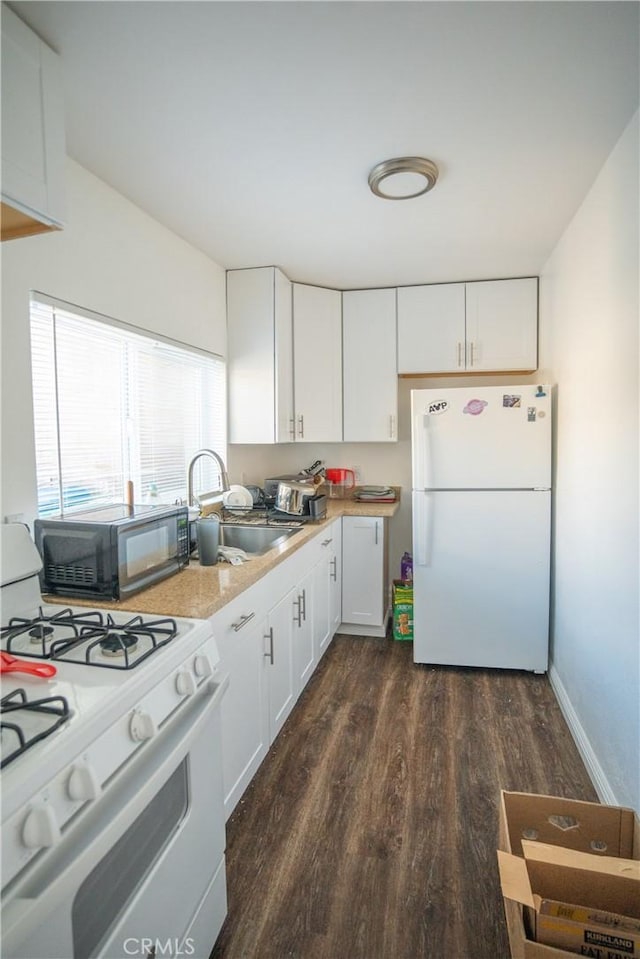 kitchen with dark wood finished floors, white cabinets, white appliances, and a sink