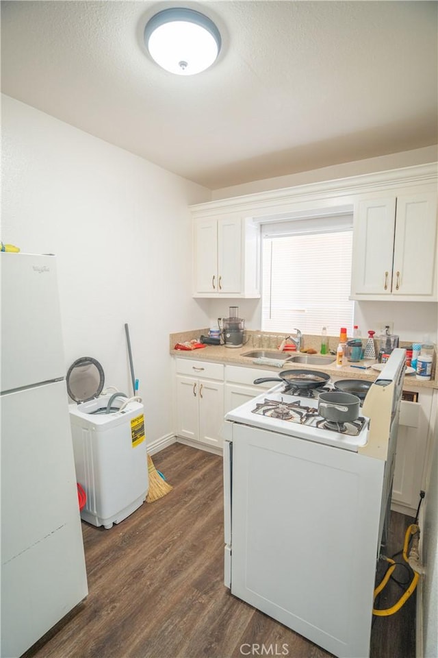 kitchen featuring washer / dryer, white appliances, dark wood-type flooring, white cabinets, and a sink
