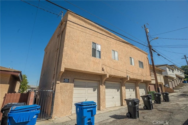 view of side of property featuring a garage, fence, and stucco siding