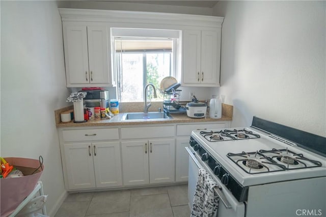 kitchen with a sink, white cabinetry, white gas range, and light countertops