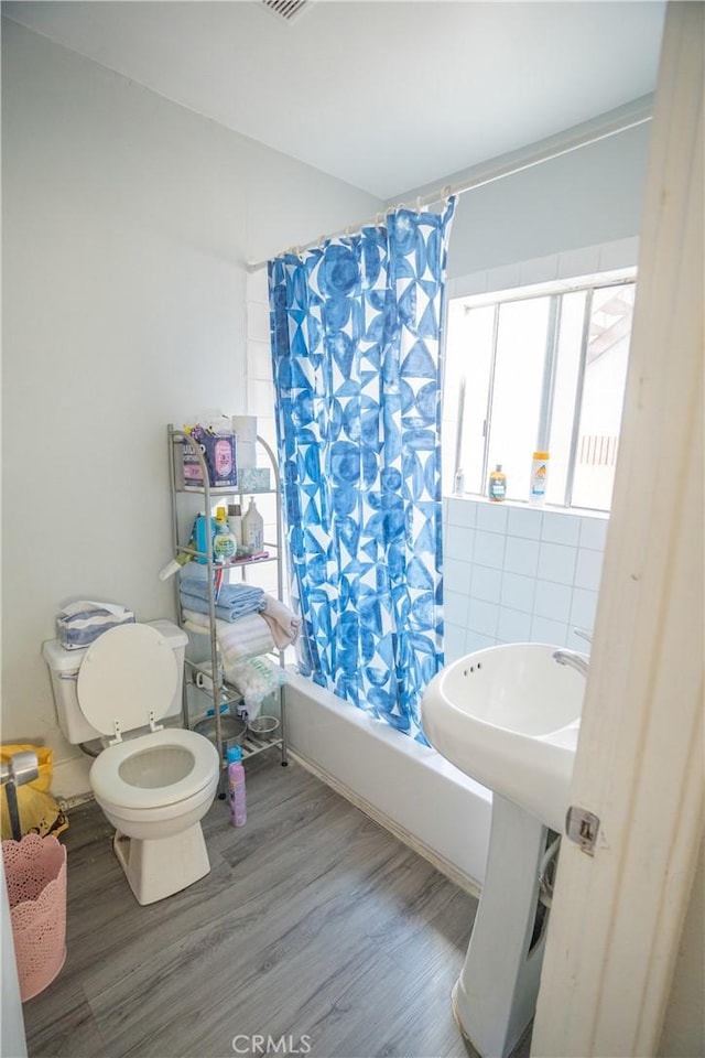 full bath featuring toilet, visible vents, wood finished floors, and shower / tub combo