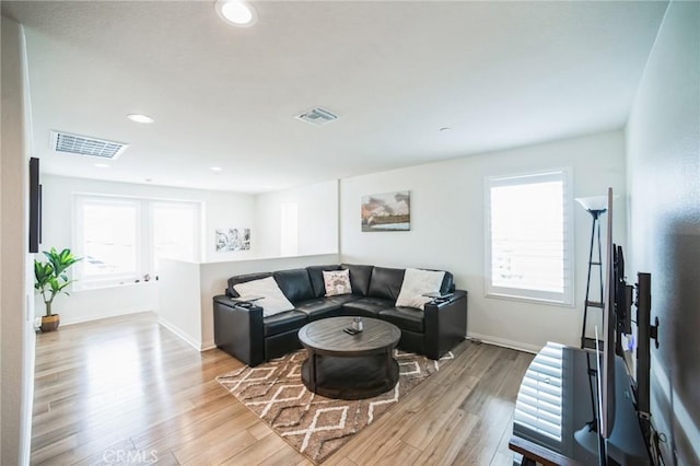 living room with light wood-style floors, baseboards, and visible vents
