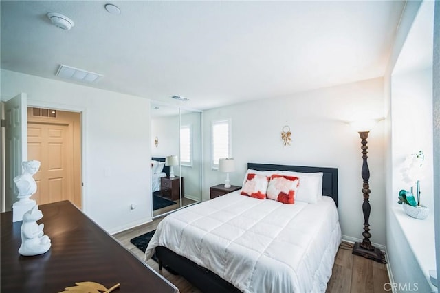 bedroom featuring wood finished floors, baseboards, and visible vents