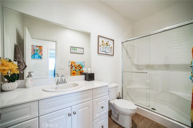 bathroom featuring a shower stall, vanity, toilet, and wood finished floors