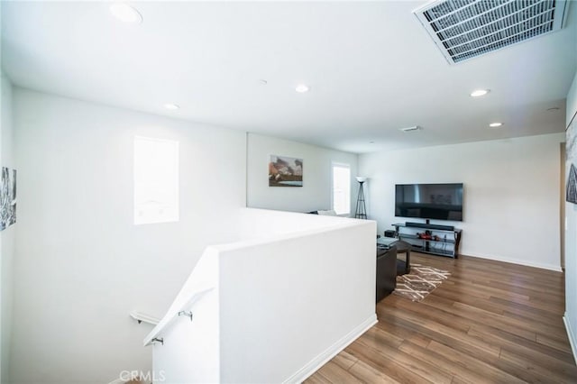 hallway with wood finished floors, visible vents, and recessed lighting