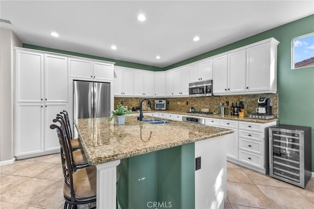 kitchen with wine cooler, appliances with stainless steel finishes, white cabinets, and a sink