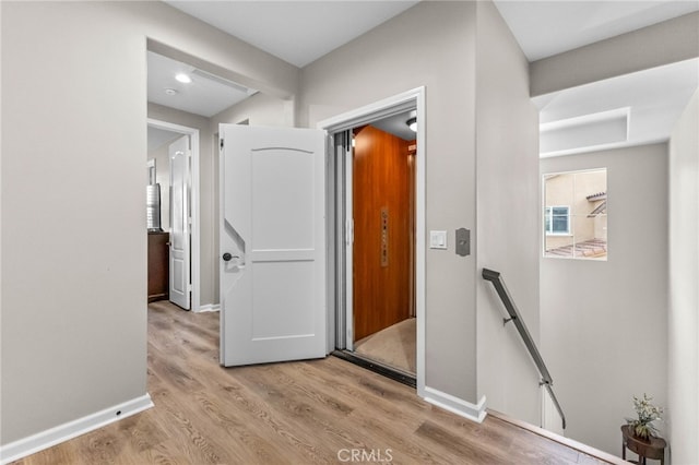 hall featuring baseboards, an upstairs landing, and wood finished floors
