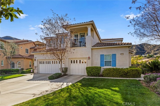 mediterranean / spanish home with driveway, a tile roof, a balcony, a front lawn, and stucco siding