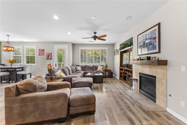 living area with baseboards, light wood-style flooring, and a fireplace
