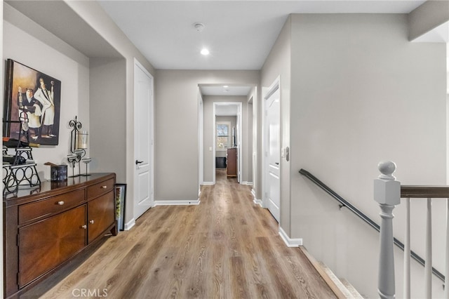 hall with recessed lighting, baseboards, an upstairs landing, and light wood-type flooring