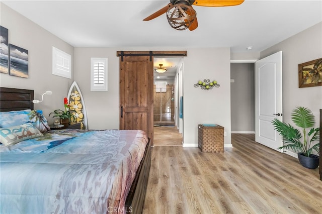 23757 Cahuilla Ct, Corona, CA 92883 - bedroom with a barn door, light wood finished floors, baseboards, and a ceiling fan