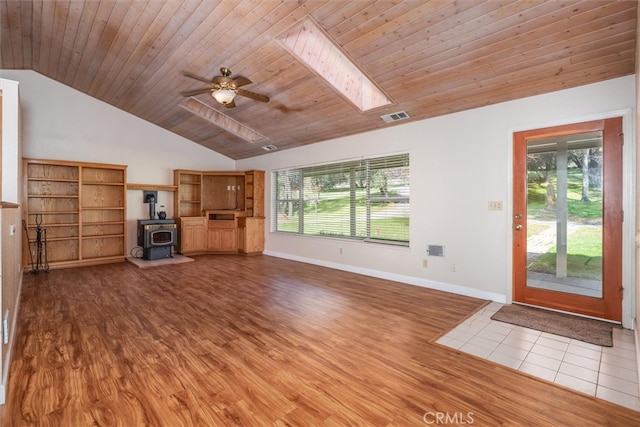 51674 Rd 426, Oakhurst, CA 93644 - unfurnished living room featuring lofted ceiling with skylight, wood finished floors, a wood stove, and visible vents