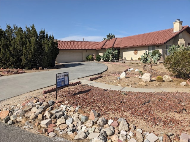 8802 Rubidoux Ave, Yucca Valley, CA 92284 - view of front of house with a tiled roof, stucco siding, curved driveway, and a chimney