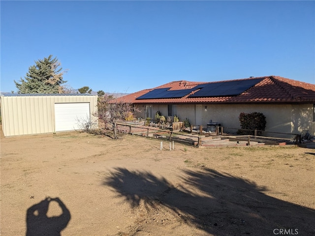 8802 Rubidoux Ave, Yucca Valley, CA 92284 - back of property featuring solar panels, an outdoor structure, a garden, and a tiled roof