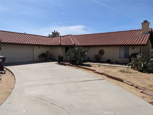 8802 Rubidoux Ave, Yucca Valley, CA 92284 - view of front of house with stucco siding, driveway, a chimney, an attached garage, and a tiled roof