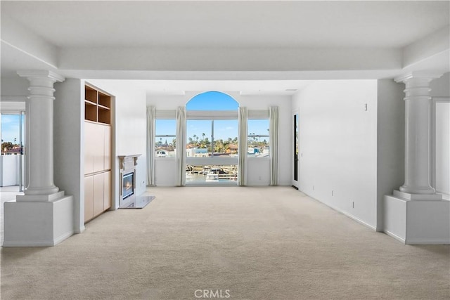 unfurnished living room with baseboards, decorative columns, a high end fireplace, and light colored carpet