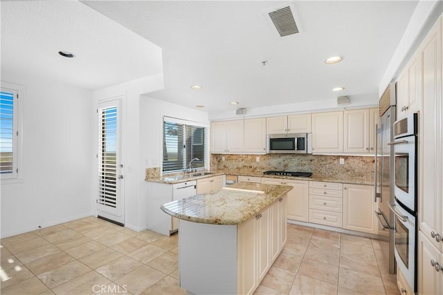 kitchen with a sink, visible vents, backsplash, white appliances, and a kitchen island
