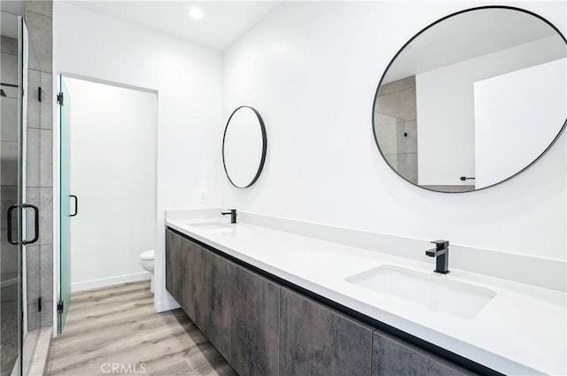 bathroom featuring a sink, wood finished floors, a stall shower, and toilet