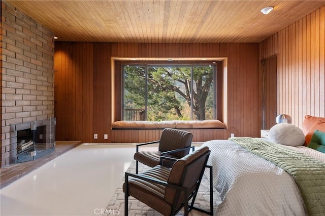 bedroom with finished concrete flooring, wooden walls, wood ceiling, and a brick fireplace