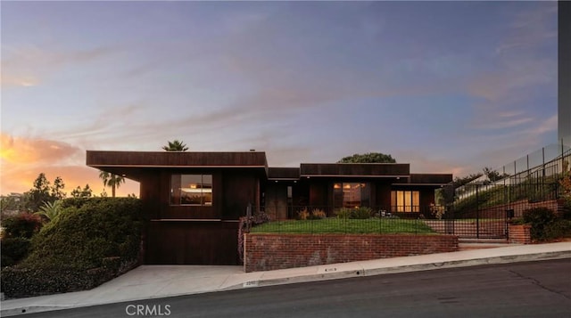 view of front facade with concrete driveway and a fenced front yard