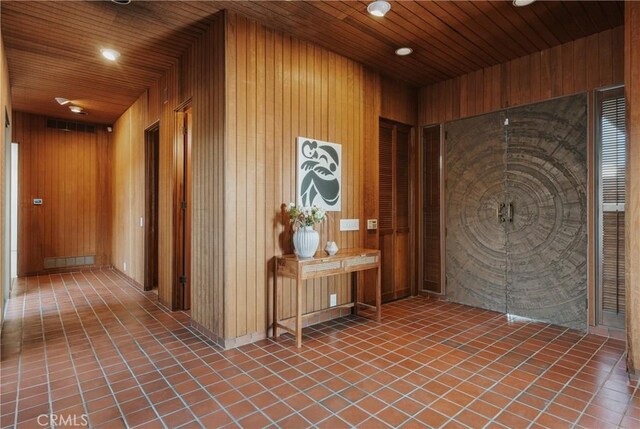 hallway featuring tile patterned floors, wooden ceiling, wood walls, and recessed lighting